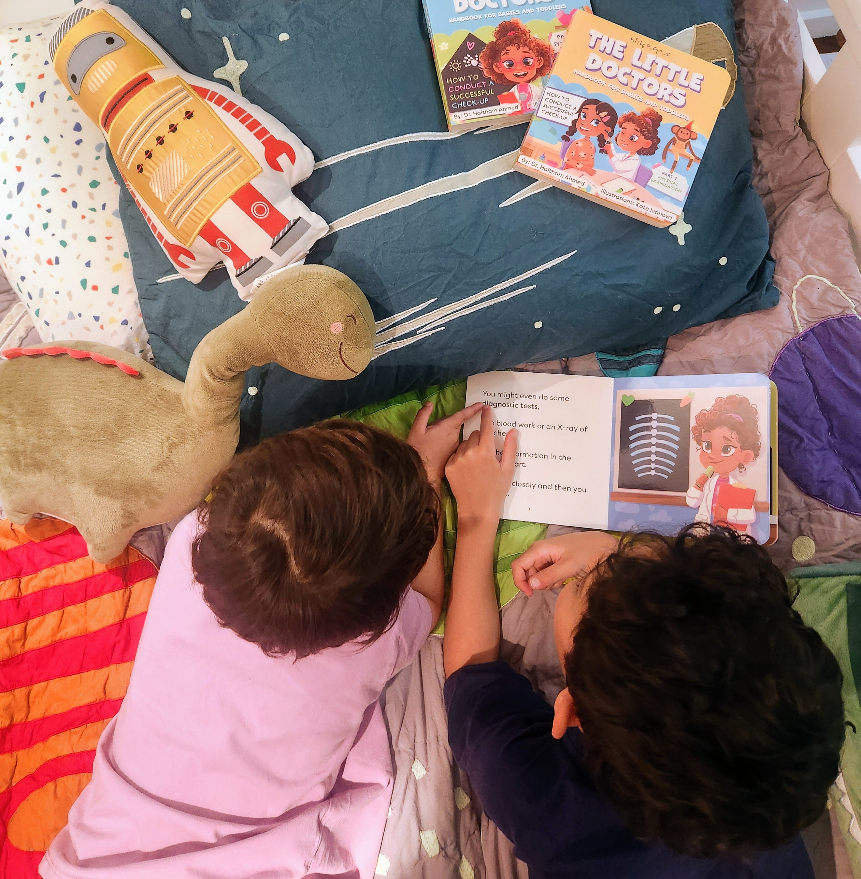 Two children reading Little Doctors Handbook for Babies and Toddlers at bedtime
