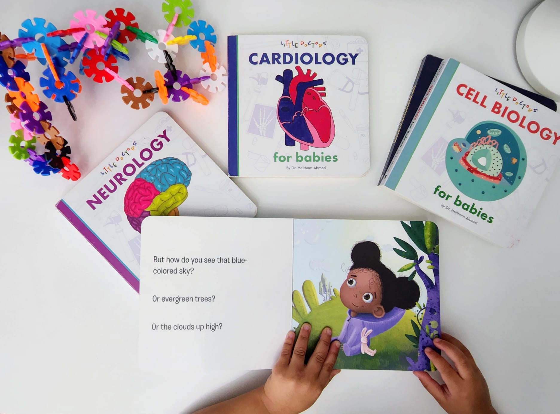 Child reading Little Doctors Ophthalmology for Babies lift-the-flap book alongside Cardiology, Neurology and Cell Biology board books